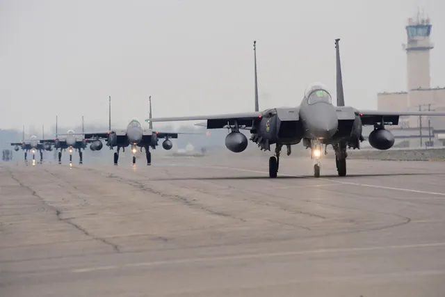 Five F-15Ks taxiing in single file past an airfield control tower