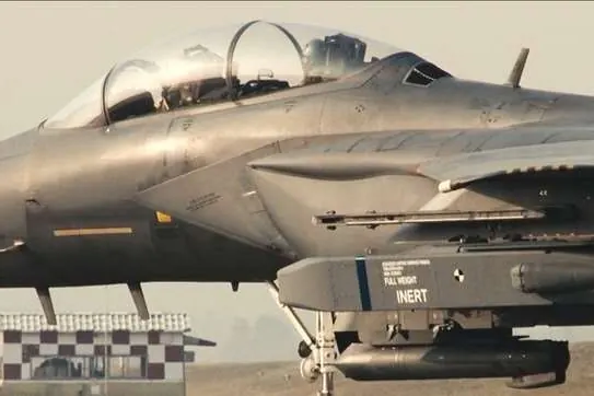 Close side view of an F-15K on the ground carrying a store stencilled INERT