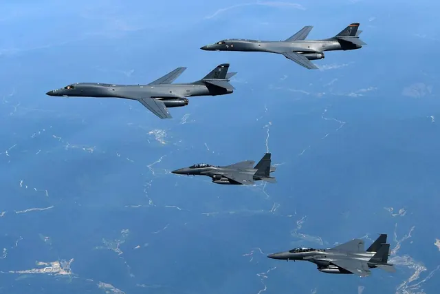 Two B-1B bombers flying above two F-15Ks over mountainous terrain