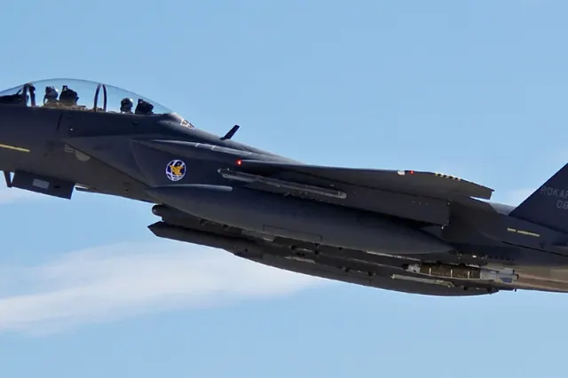 An F-15K in flight seen from the side against a pale blue sky