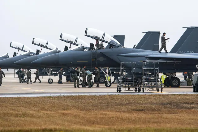 Four F-15Ks parked in a row with canopies open and crews working around them
