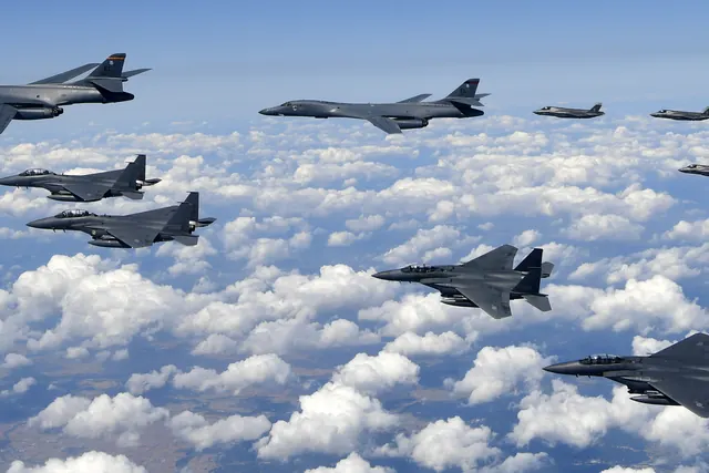 A large mixed formation of bombers, stealth fighters and F-15Ks above a cloud field