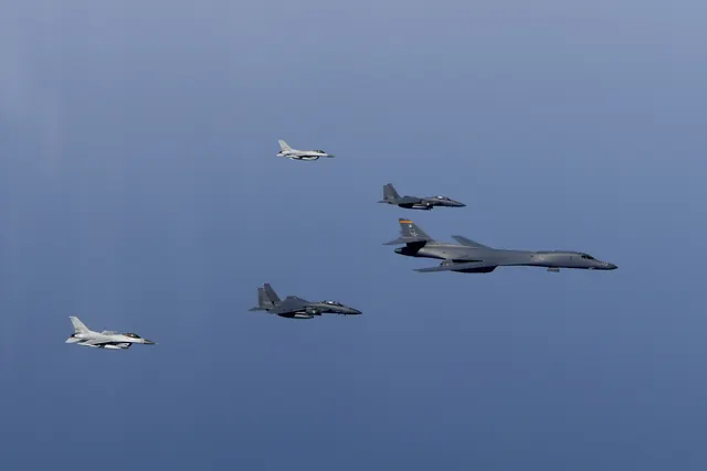 Two F-16s, two F-15Ks and a B-1B bomber in formation against clear blue sky