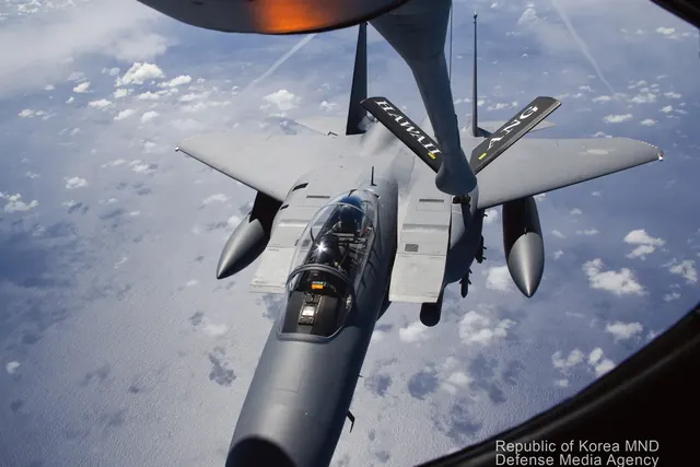 An F-15K taking fuel from a tanker, photographed through a window on the tanker